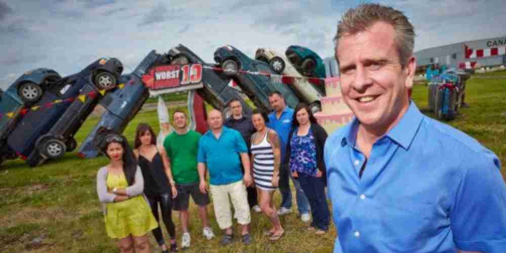 A host for the Worst Driver reality show standing in front of a car pileup.