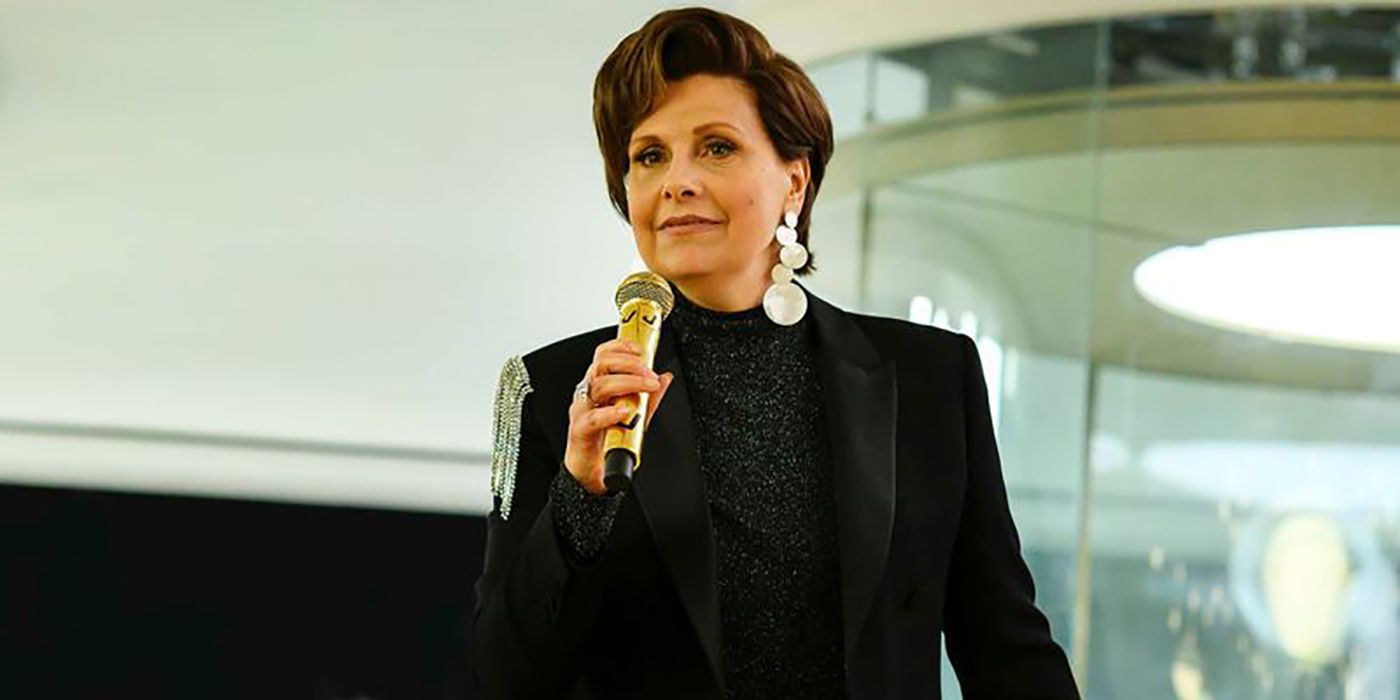 Karen from Avenue 5 in a black blazer holding a microphone