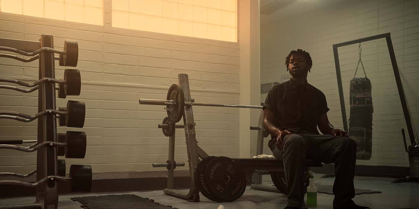 Christopher Scarver sitting on a bench in the weights room in prison in Monster: The Jeffrey Dahmer Story
