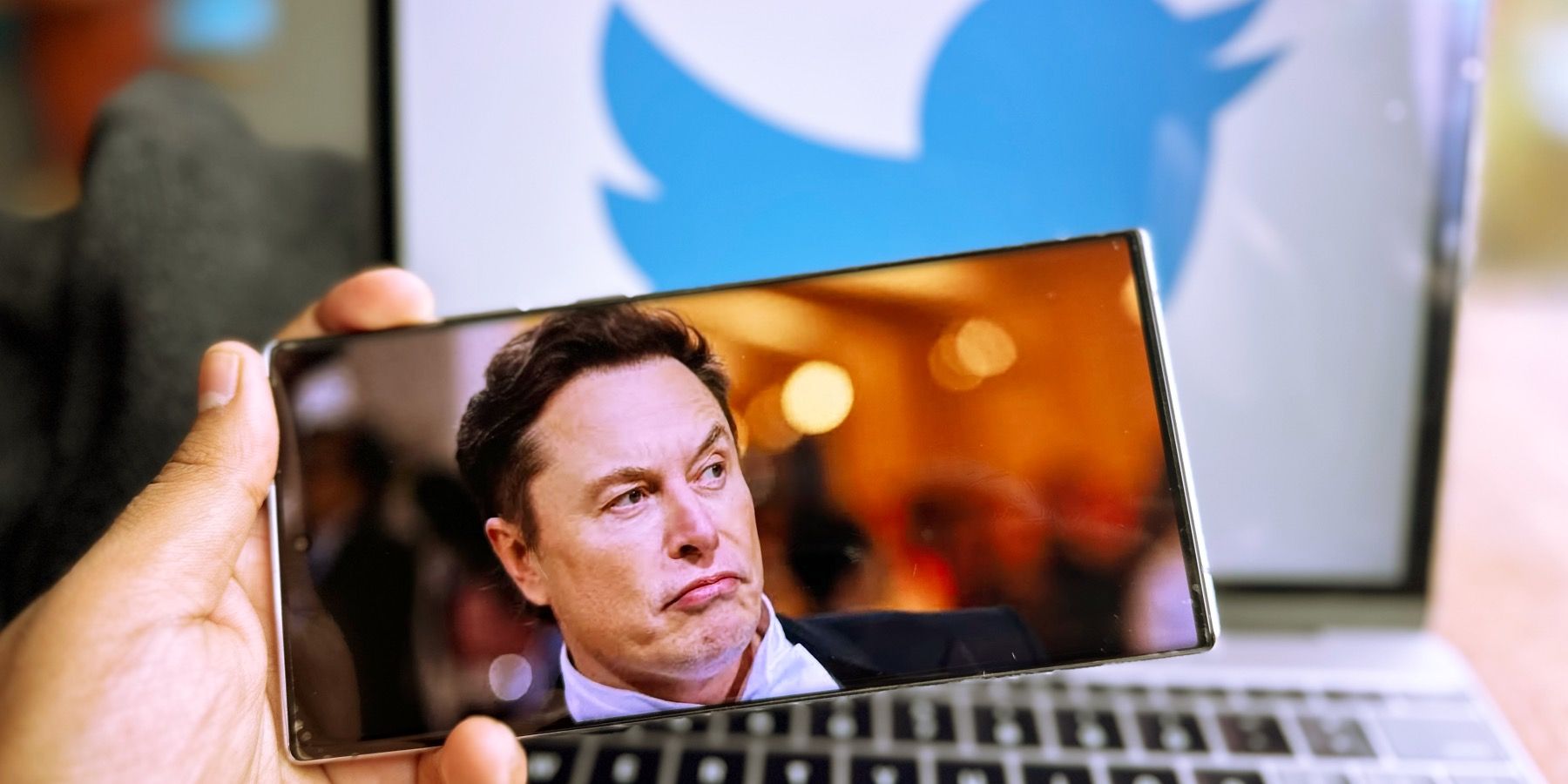Elon Musk against the backdrop of a Twitter insignia.