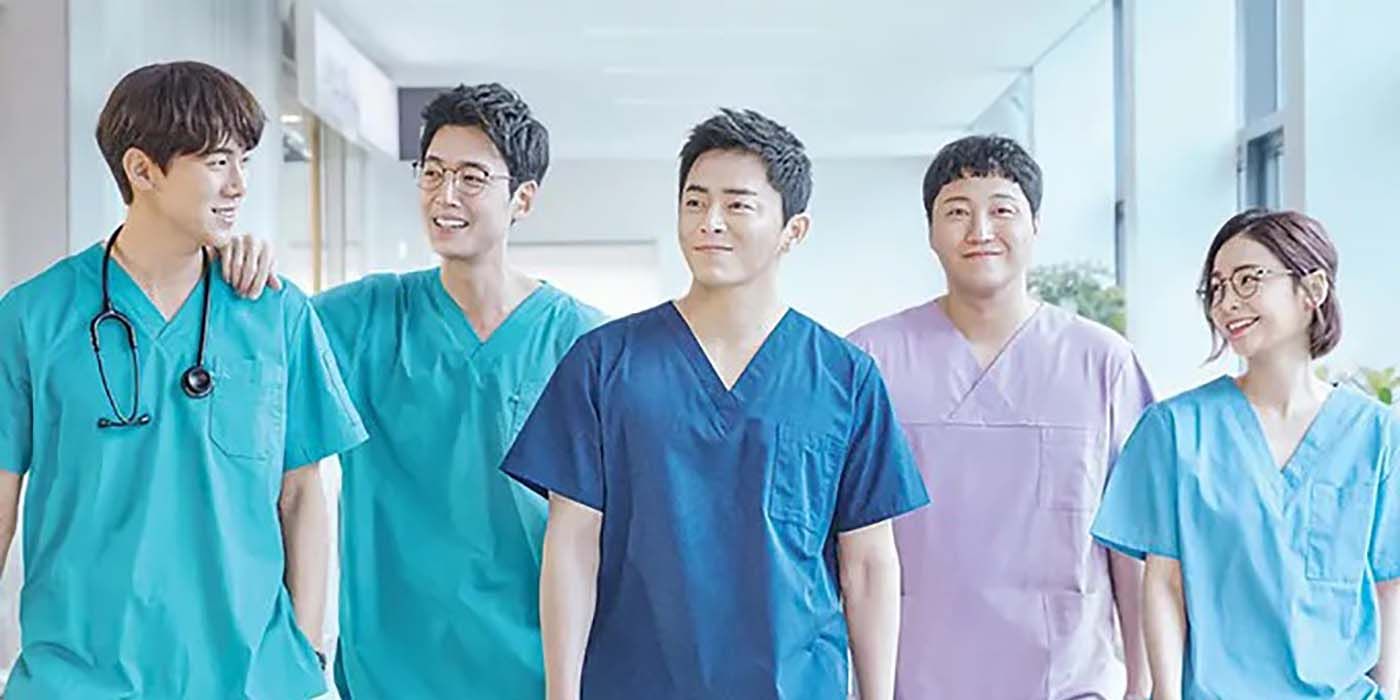 Los miembros principales del elenco de Hospital Playlist con uniformes médicos caminando juntos.