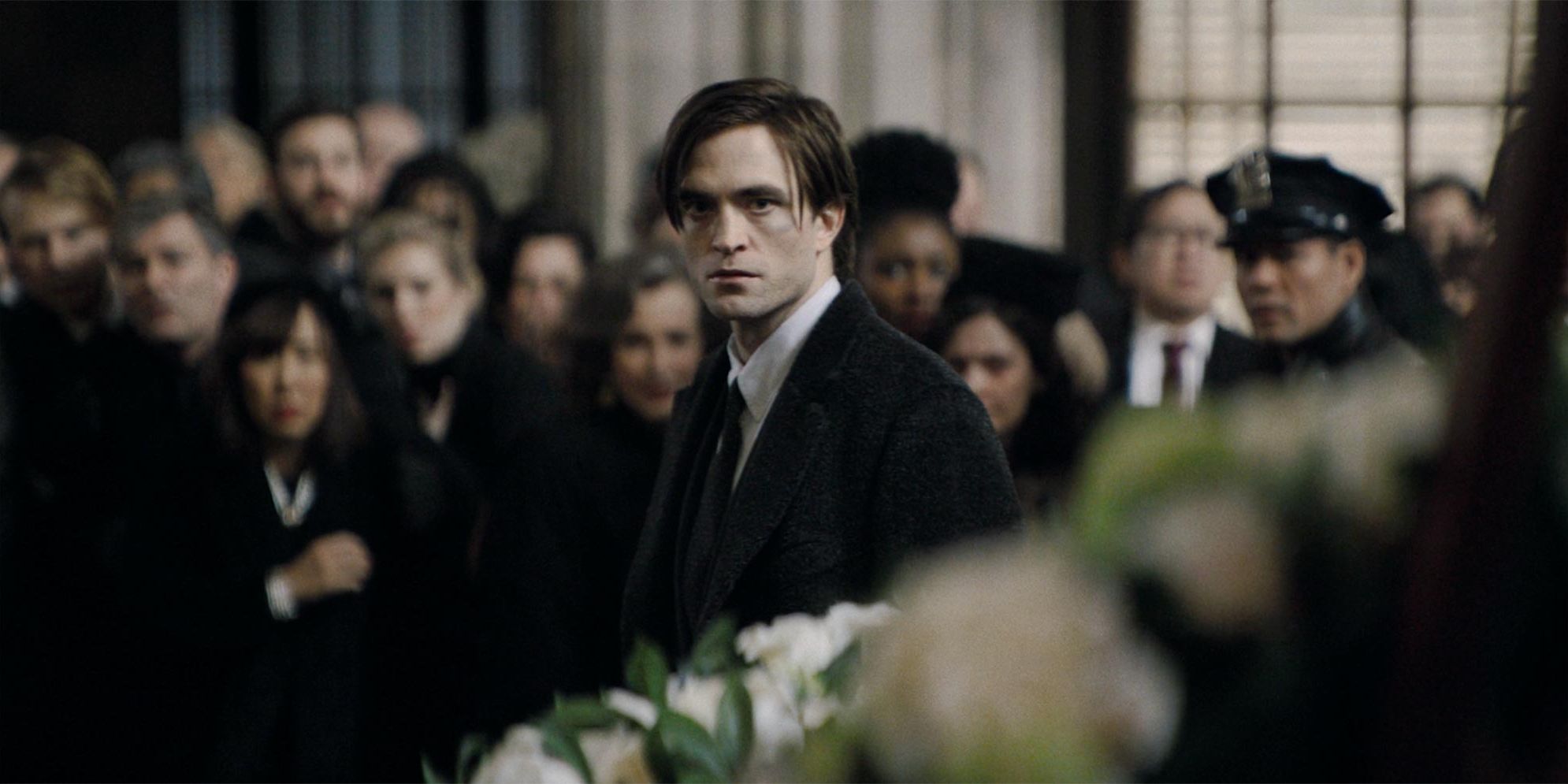 Bruce Wayne at a funeral, staring intensely into the distance in The Batman.