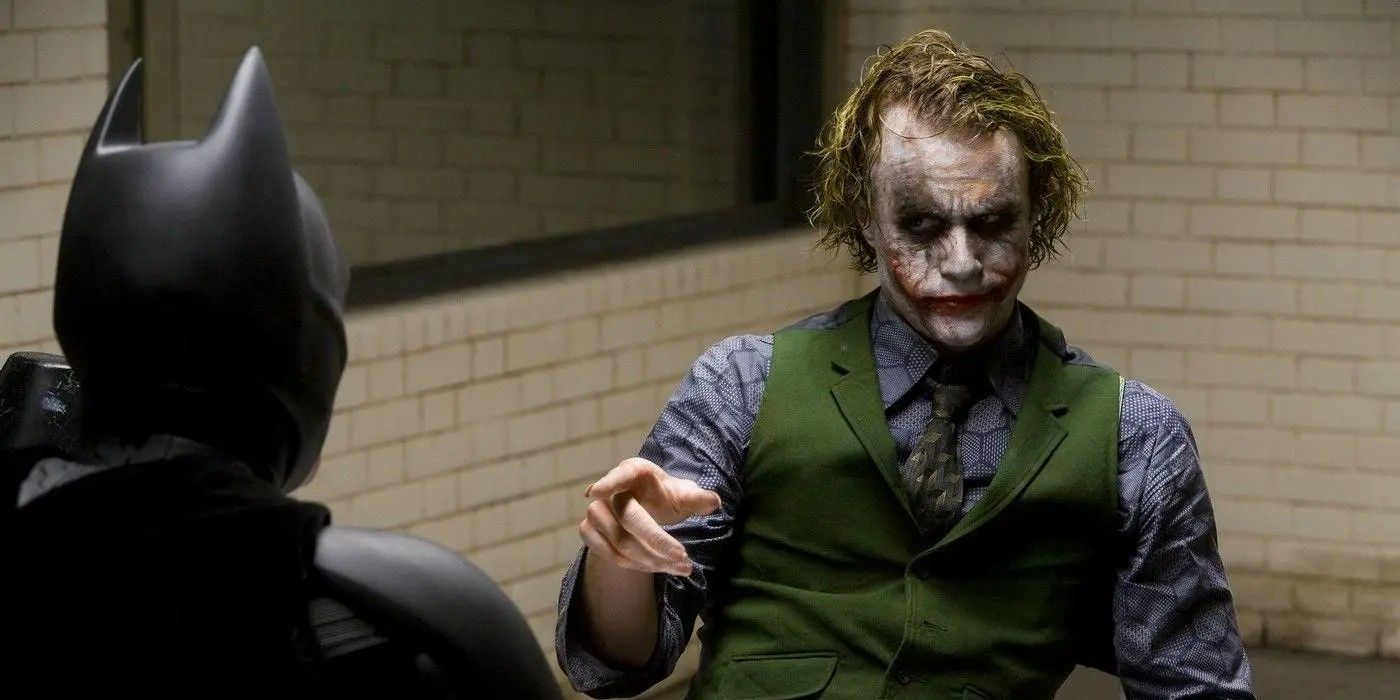 Heath Ledger como o Coringa apontando para o Batman de Christian Bale em O Cavaleiro das Trevas