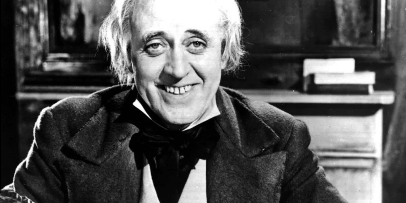 Scrooge smiling in the 1951 version of A Christmas Carol in black and white. 