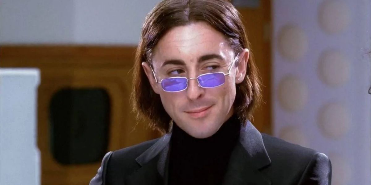 Alan Cumming as Wyatt smirking and wearing small sunglasses in Josie and the Pussycats