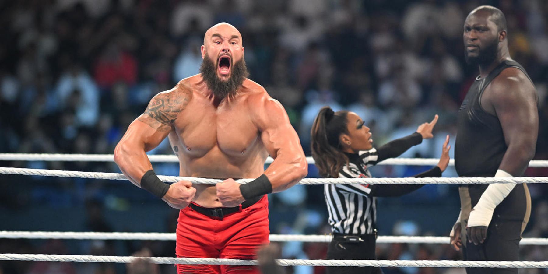 Braun Strowman performs during WWE Crown Jewel while Omos looks on.