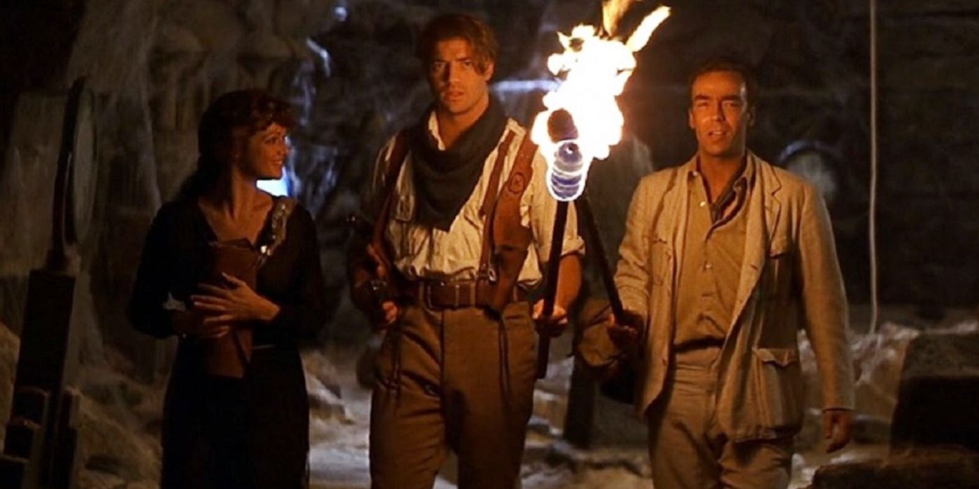 Brendan Fraser segurando uma tocha flamejante ao lado de Rachel Weisz e John Hannah em A Múmia.