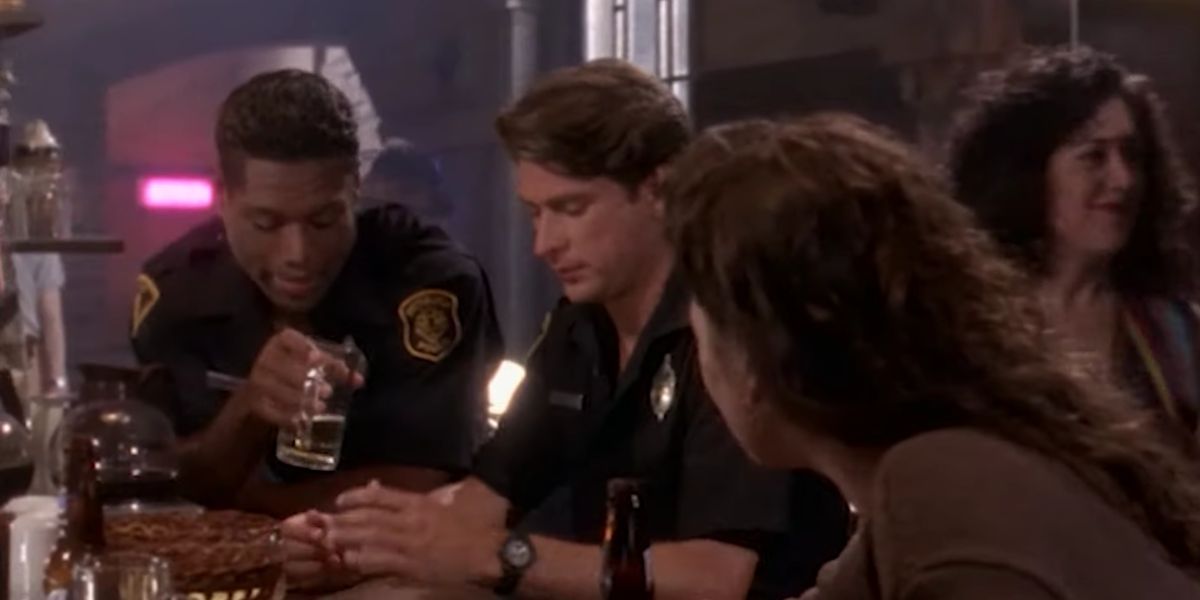 Christopher Judge berbagi minuman dengan teman sebagai Petugas Richard Stiles di Sirens 1993