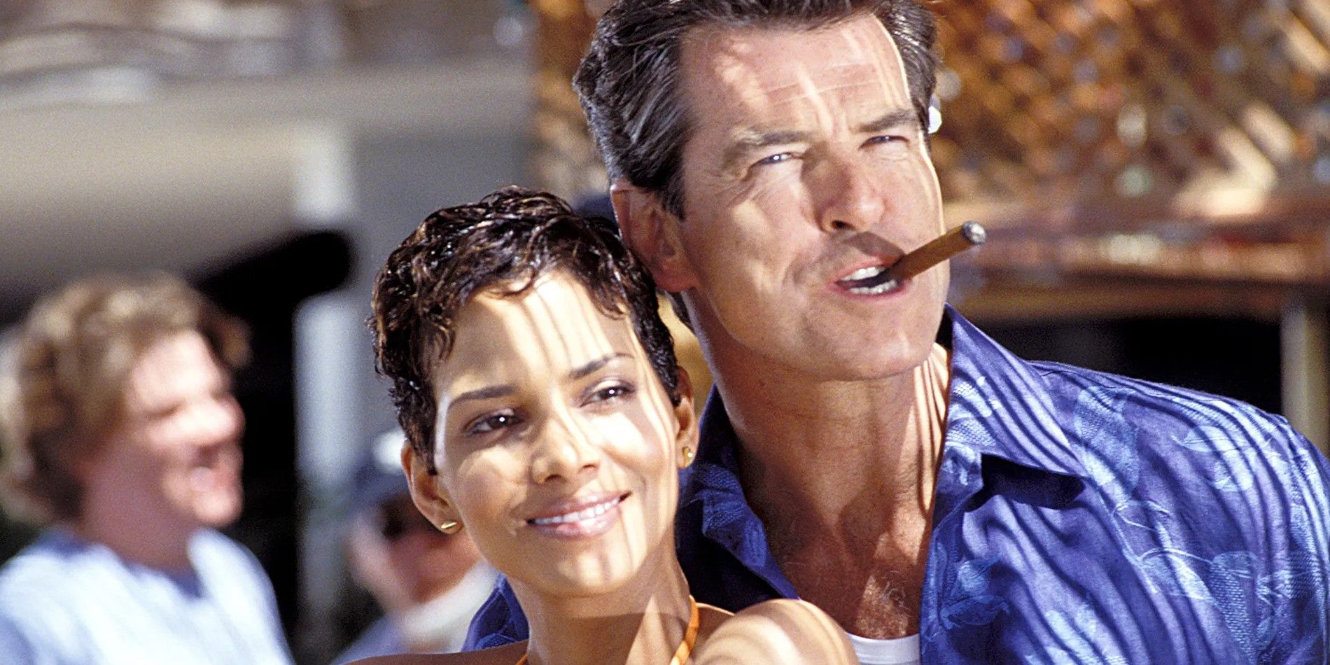 Die Another Day - Pierce Brosnan as James Bond smoking a cigar and Halle Berry as Jinx standing in the sunshine 