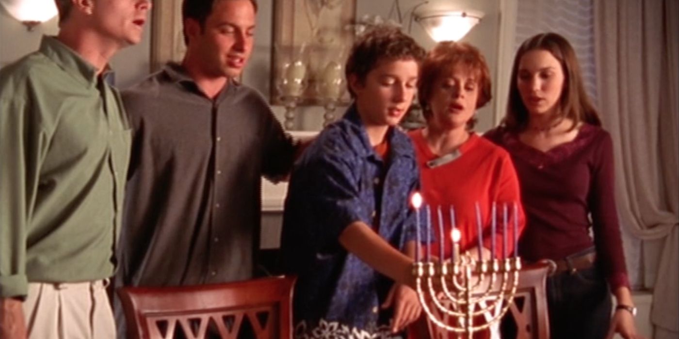 Louis lighting a candle on a Menorah during Hanukkah in Even Stevens. 