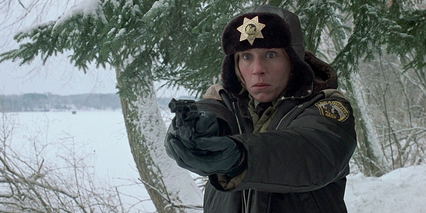 Marge (Frances McDormand) pointing a gun and looking afraid in a snowy forest in Fargo.
