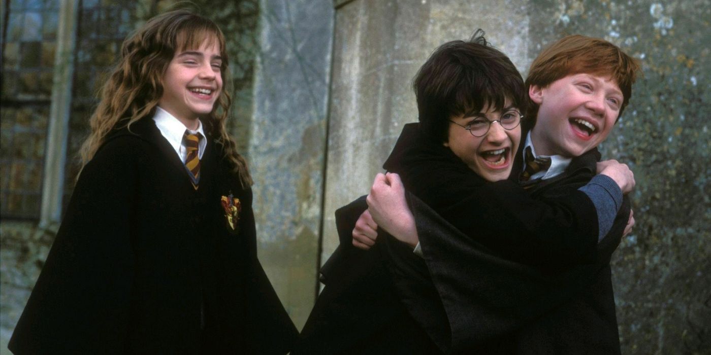 Harry, Ron, and Hermione laughing and hugging in Harry Potter. 