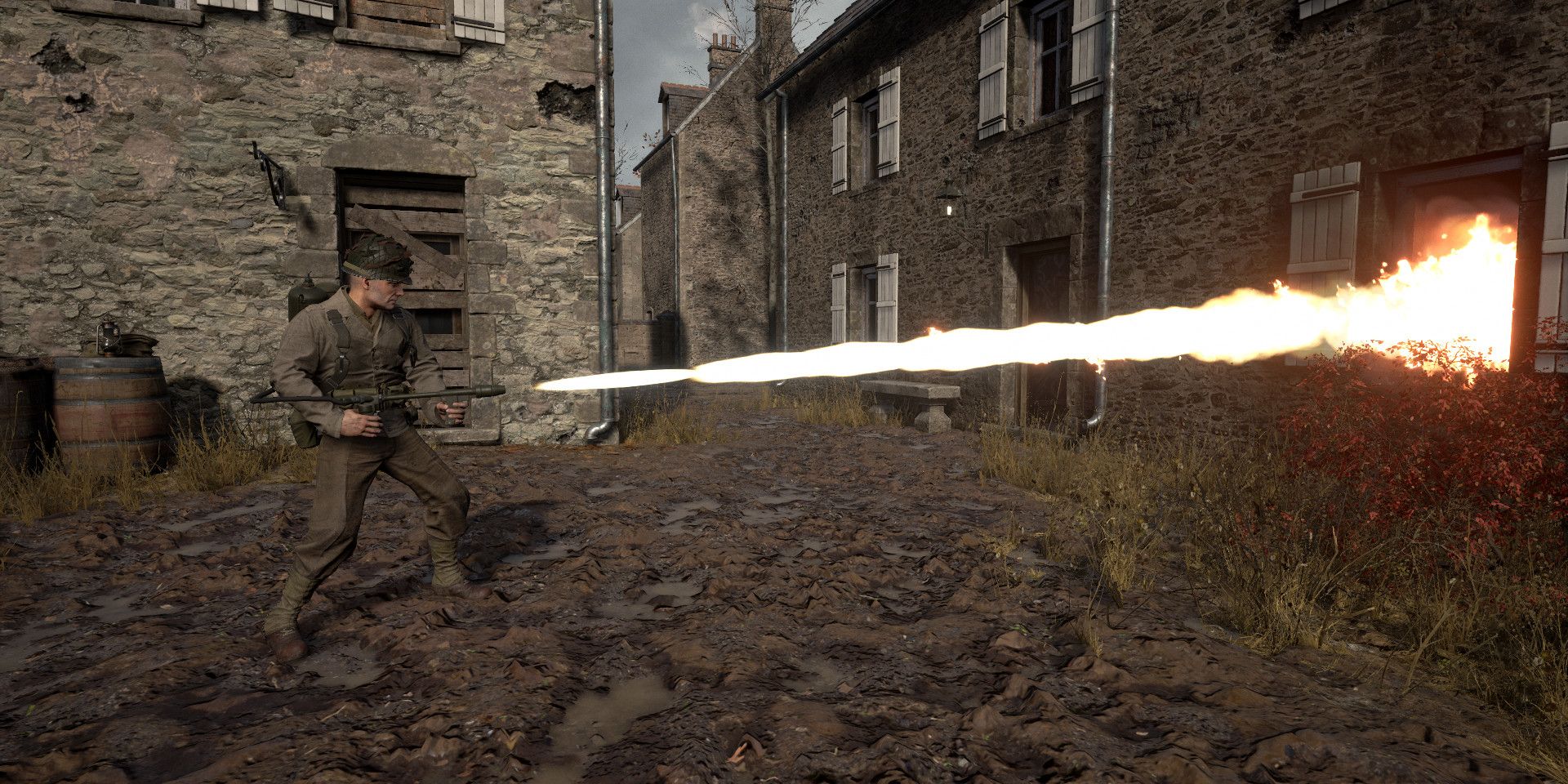 A soldier in Hell Let Loose using a flamethrower on a building