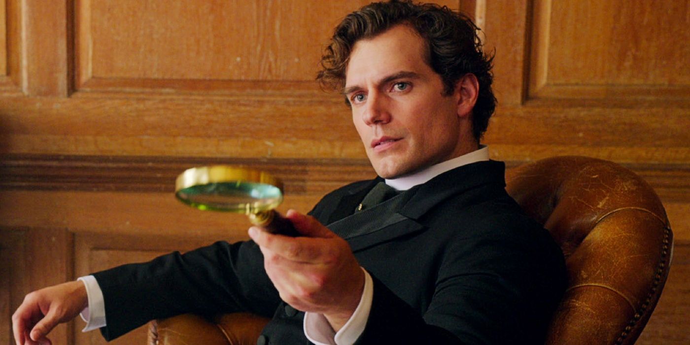 Henry Cavill as Sherlock Holmes holds a magnifying glass in a scene from Enola Holmes 2.