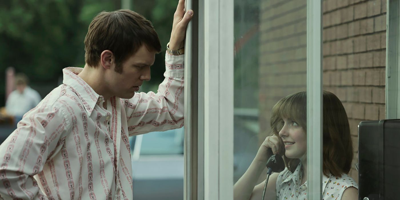 Jake Lacy as Robert Berchtold looking at Mckenna Grace as Jan Broberg, who's in a phone booth in A Friend of the Family
