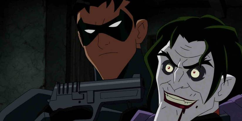 A beaten Joker being held at gunpoint by Jason Todd in Under the Red Hood.