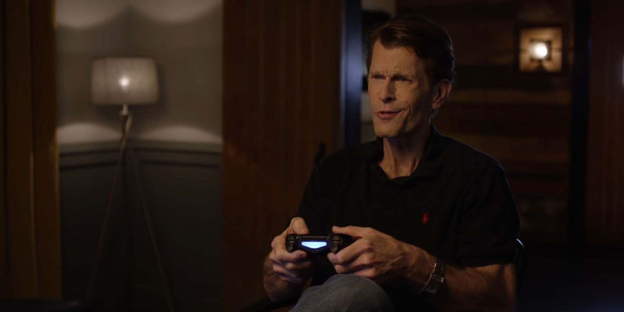 Kevin Conroy segurando um controle de PS4 em vídeo promocional de Batman Arkham Knight