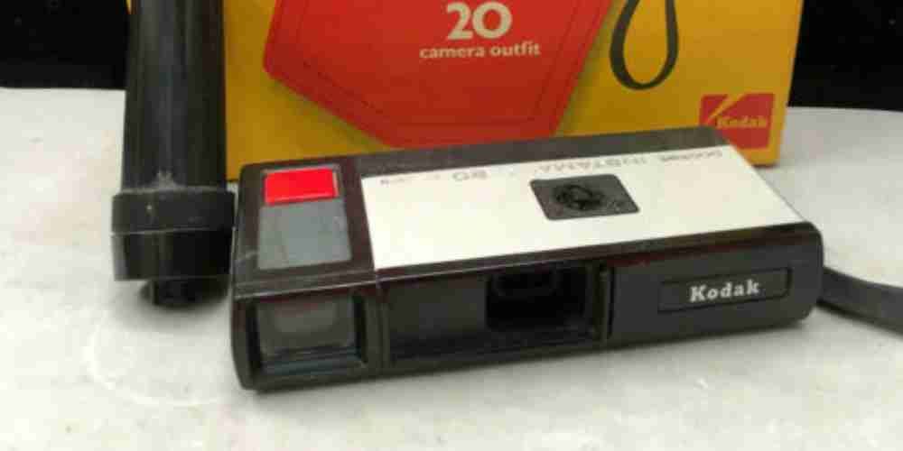 A Kodak camera lying in front of a box.