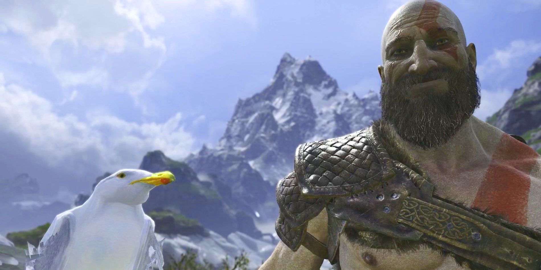God of War's Kratos is seen standing on top of a high mountaintop, sporting a rare smile from the character while standing next to a confused looking seagull.