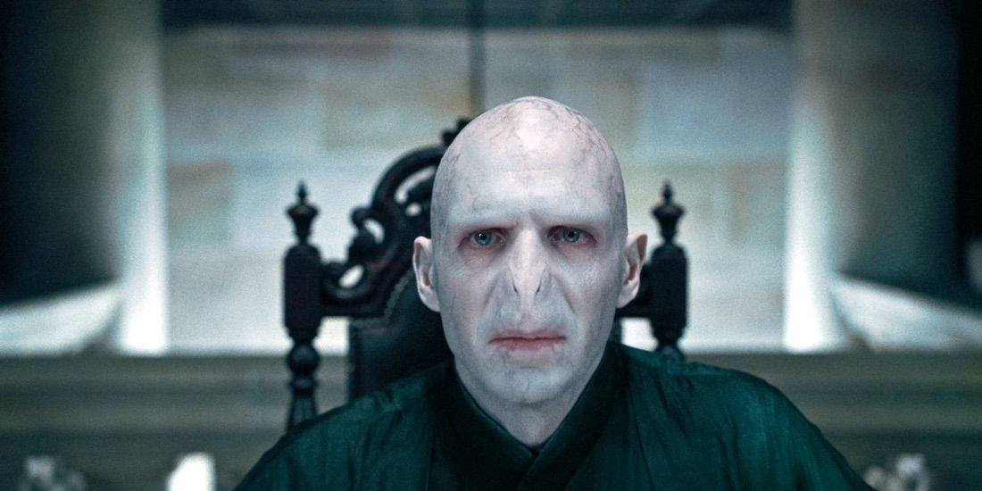 Lord Voldemort sentado a la cabecera de una mesa en Harry Potter. 