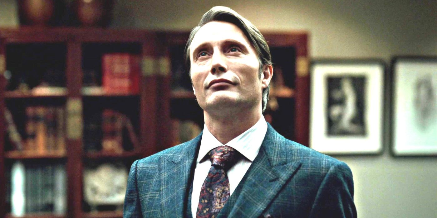 Mads Mikkelsen as Hannibal Lecter in Hannibal dressed in a sharp looking suit in a fancy office looking up at something