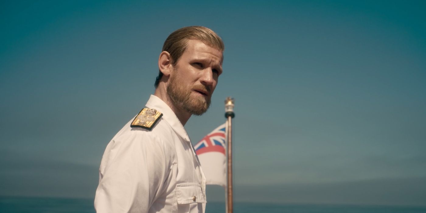 The Crown: Prince Philip (Matt Smith) standing before an English naval flag while wearing his uniform and looking into the distance