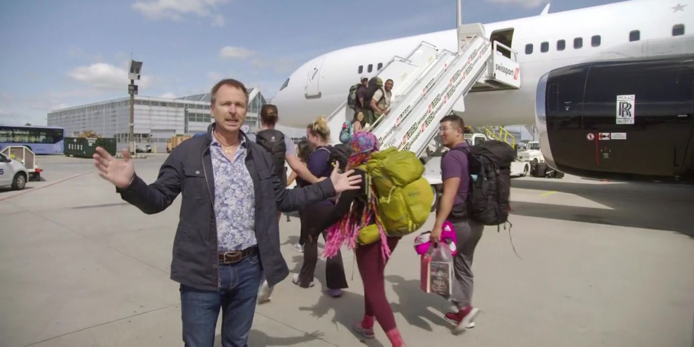 Phil Keoghan talking as contestants go inside the plane in Amazing Race