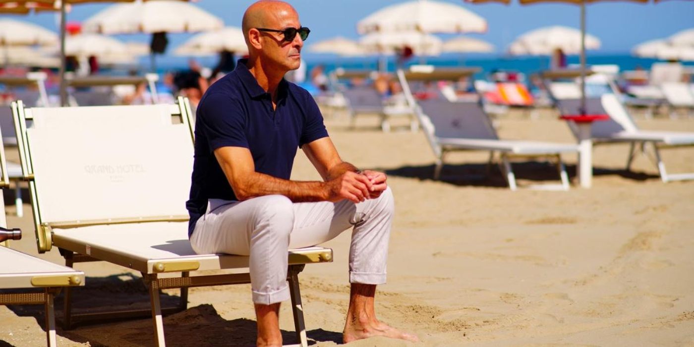 Stanley Tucci sitting on the beach in Stanley Tucci: Searching For Italy