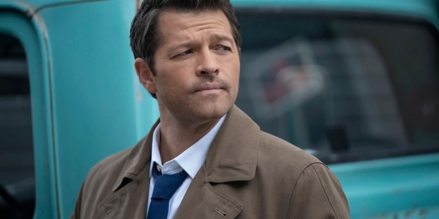 Castiel looking serious standing in front of a blue car in Supernatural