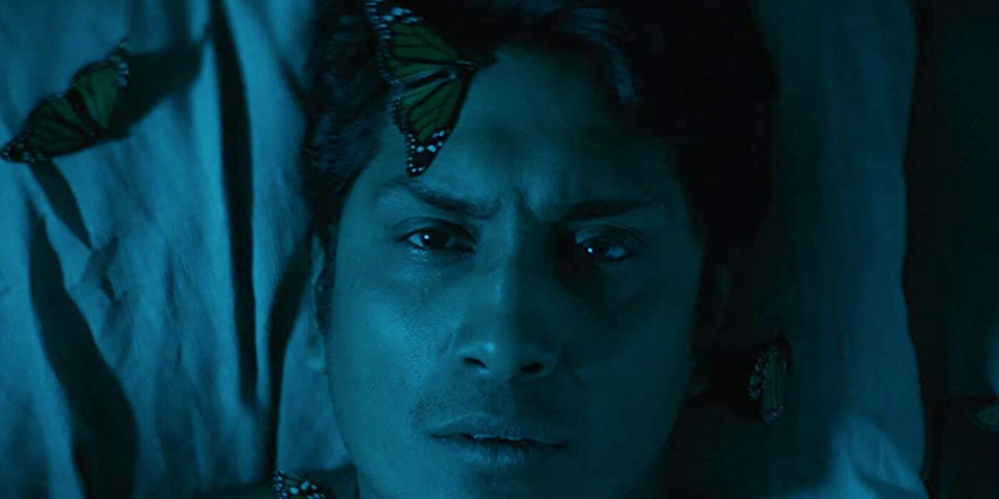 Tenoch Huerta laying on bed with butterflies on his body in Son of Monarchs Cropped (1)