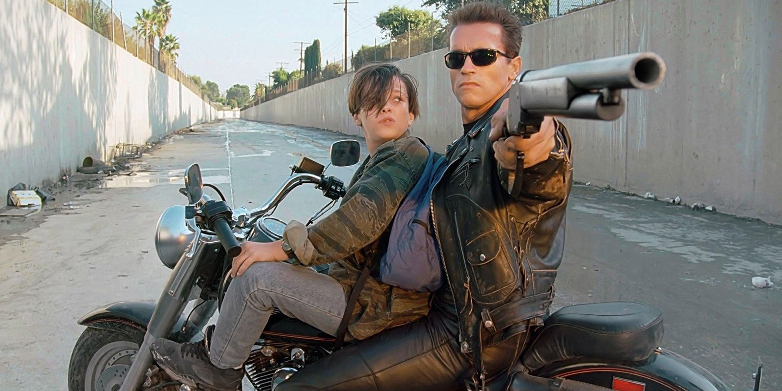 The T-800 and John Connor on a motorcycle with T-800 pointing a gun in Terminator 2 Judgment Day
