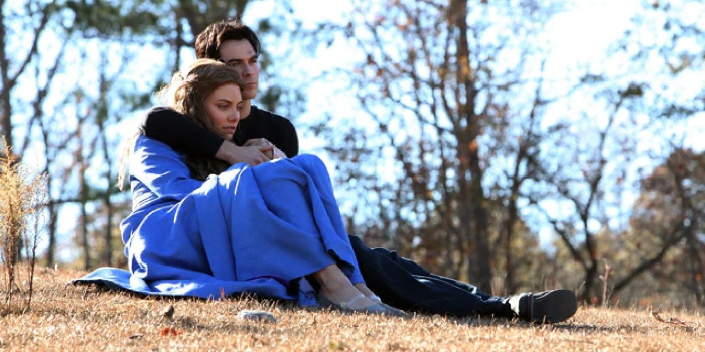Rose e Damon sentados juntos em um campo em The Vampire Diaries