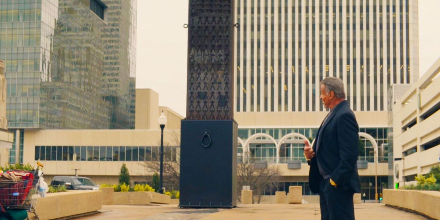 Sylvester Stallone como Dwight se encuentra en un pequeño parque de la ciudad mirando los edificios en una escena de Tulsa King