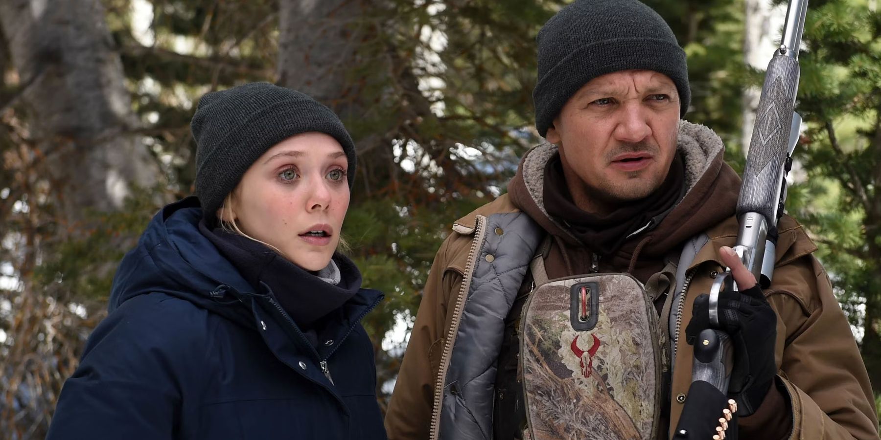 Elizabeth Olsen and Jeremy Renner as Jane Banner and Cory Lambert standing in the woods in Wind River.