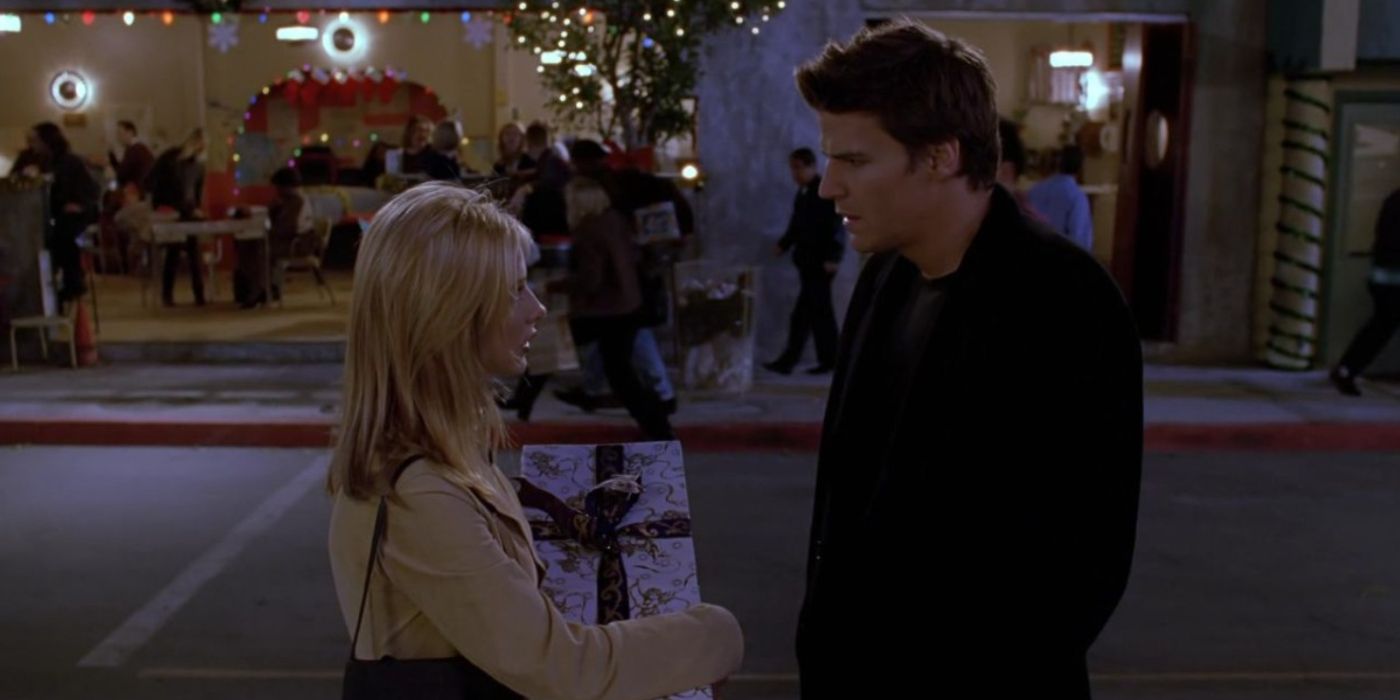 Buffy segurando um presente de Natal na mão conversando com Angel na rua em Buffy the Vampire Slayer. 