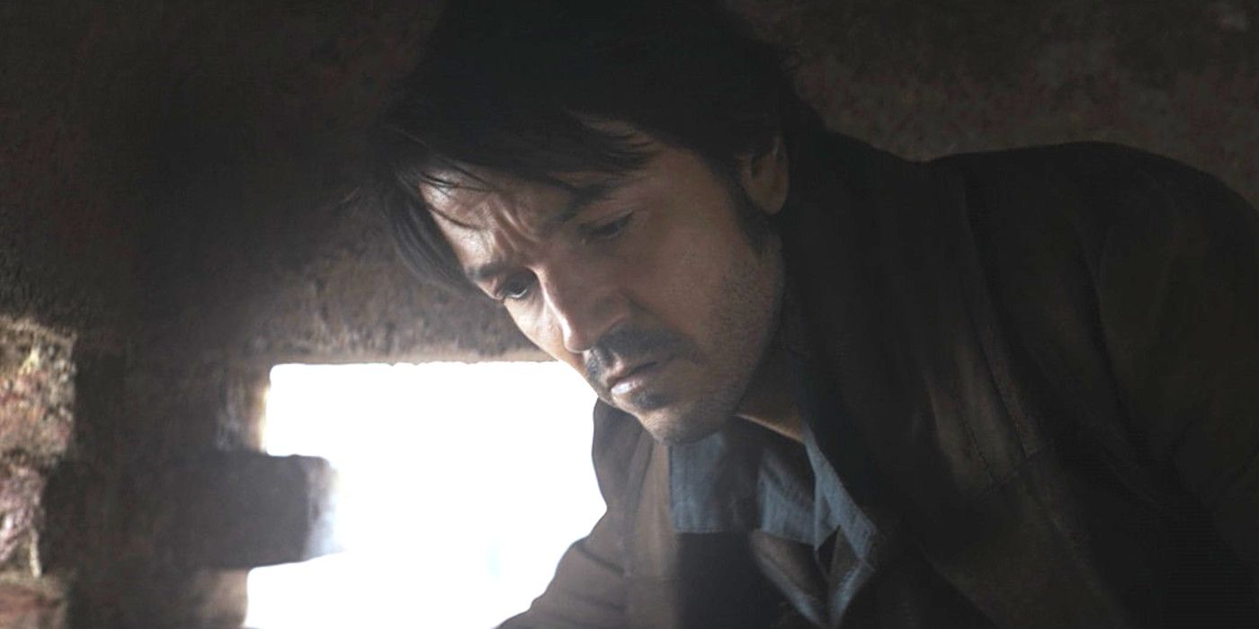 Diego Luna dans le rôle de Cassian dans Andor saison 1 accroupi dans un petit espace et regardant vers le bas, peut-être bouleversé