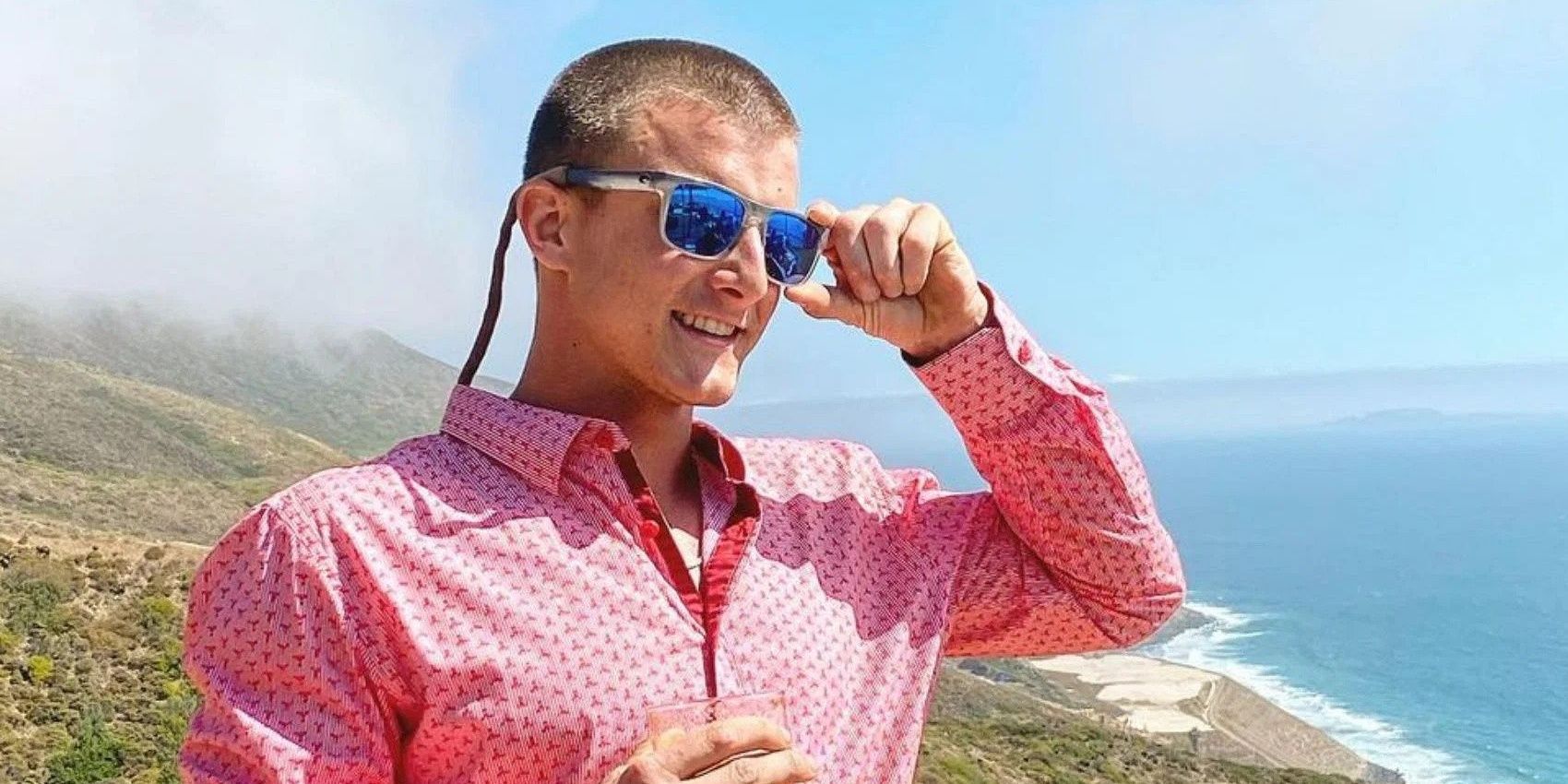 Kyle Dickard Below Deck Adventure in pink shirt and sunglasses ocean background