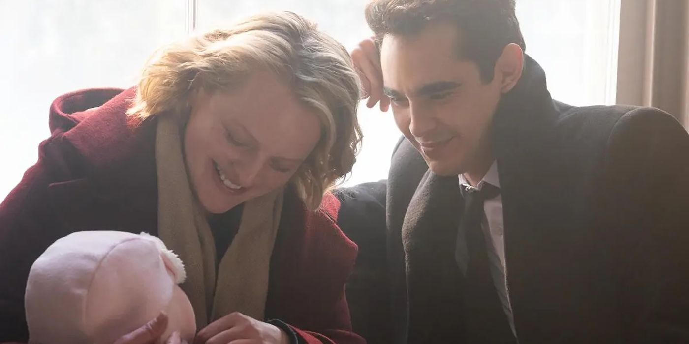 June and Nick from The Handmaid's Tale sitting together by a window, doting over Nichole