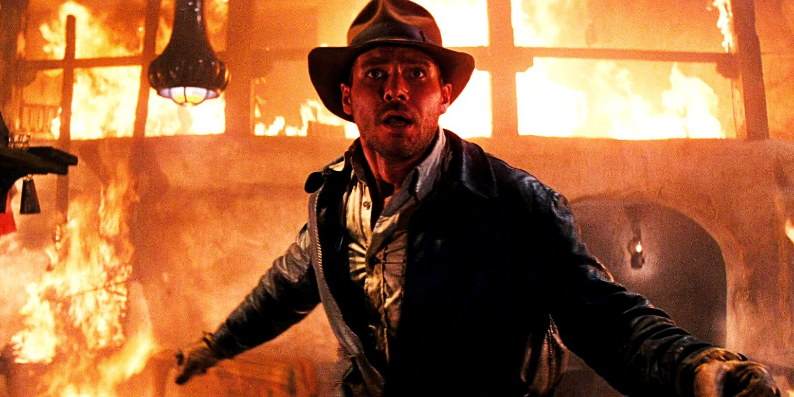 Harrison Ford as Indiana Jones standing in front of fire in Raiders of the Lost Ark