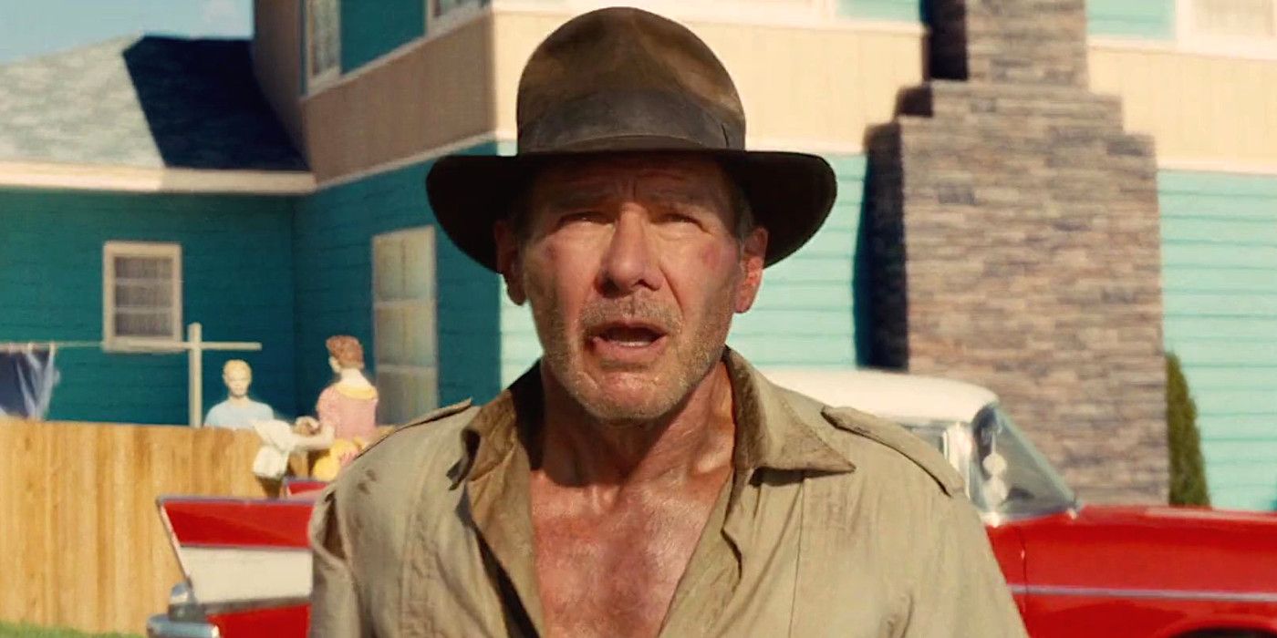 Harrison Ford as Indy in Indiana Jones and the Kingdom of the Crystal Skull gazing up in bewilderment while backdropped by a fake 1950s town from an atomic testing site