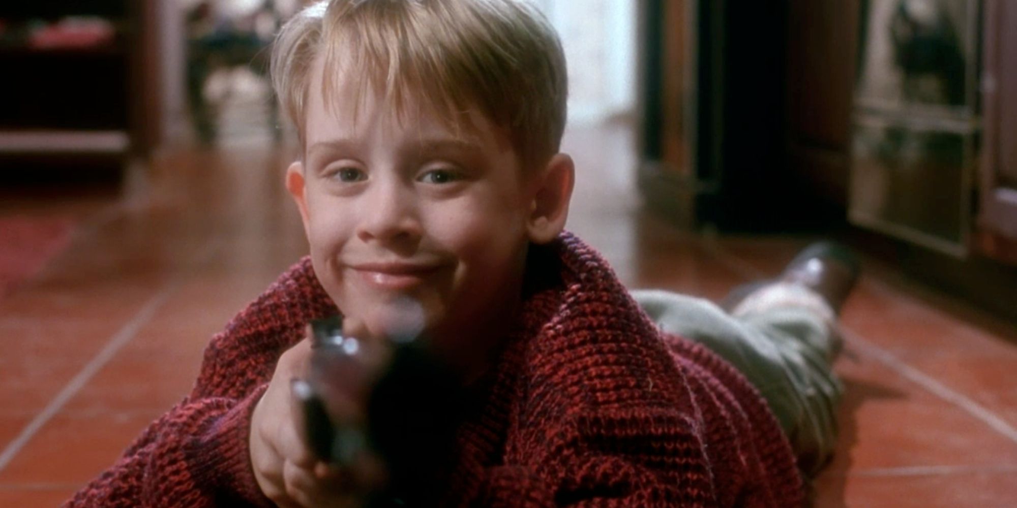 Kevin McCallister aiming his BB gun at camera in Home Alone (1990)