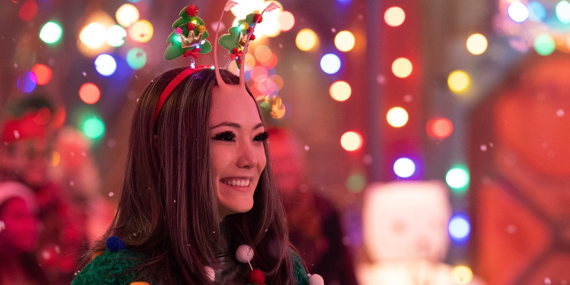 Pom Klementieff as Mantis smiles surrounded by Christmas lights in Guardians of the Galaxy Holiday Special