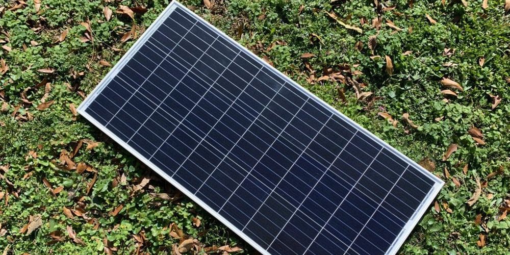 A Renogy 100 Watt Solar Panel lies on the grass