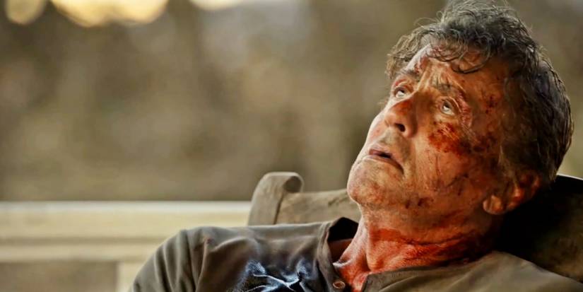Sylvester Stallone as John Rambo bloodied and tired sitting in a rocking chair in Rambo: Last Blood.