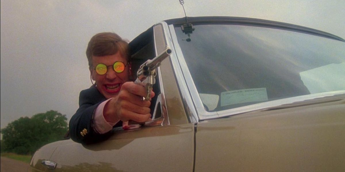 Een man leunt uit een raam met een pistool in Texas Chainsaw Massacre 2.
