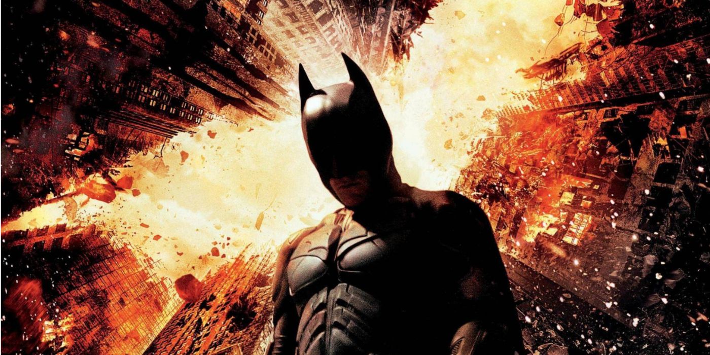 Batman standing before a flaming bat symbol making up the Gotham cityscape.