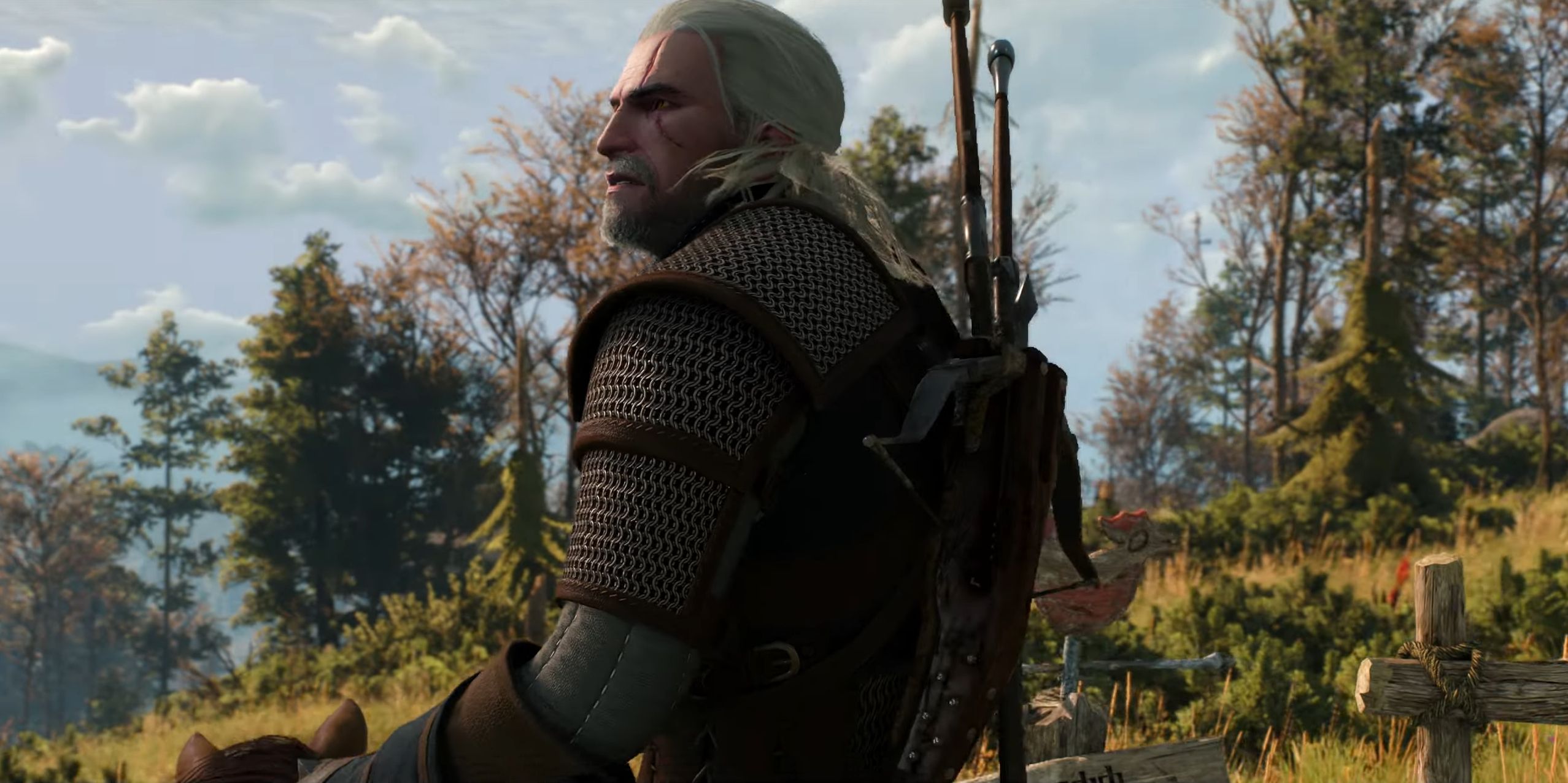 Geralt from The Witcher 3 is seen looking off into the distance while riding his horse.  He wears impressive chain mail armor and two swords, while wooden fences and trees fill the background.