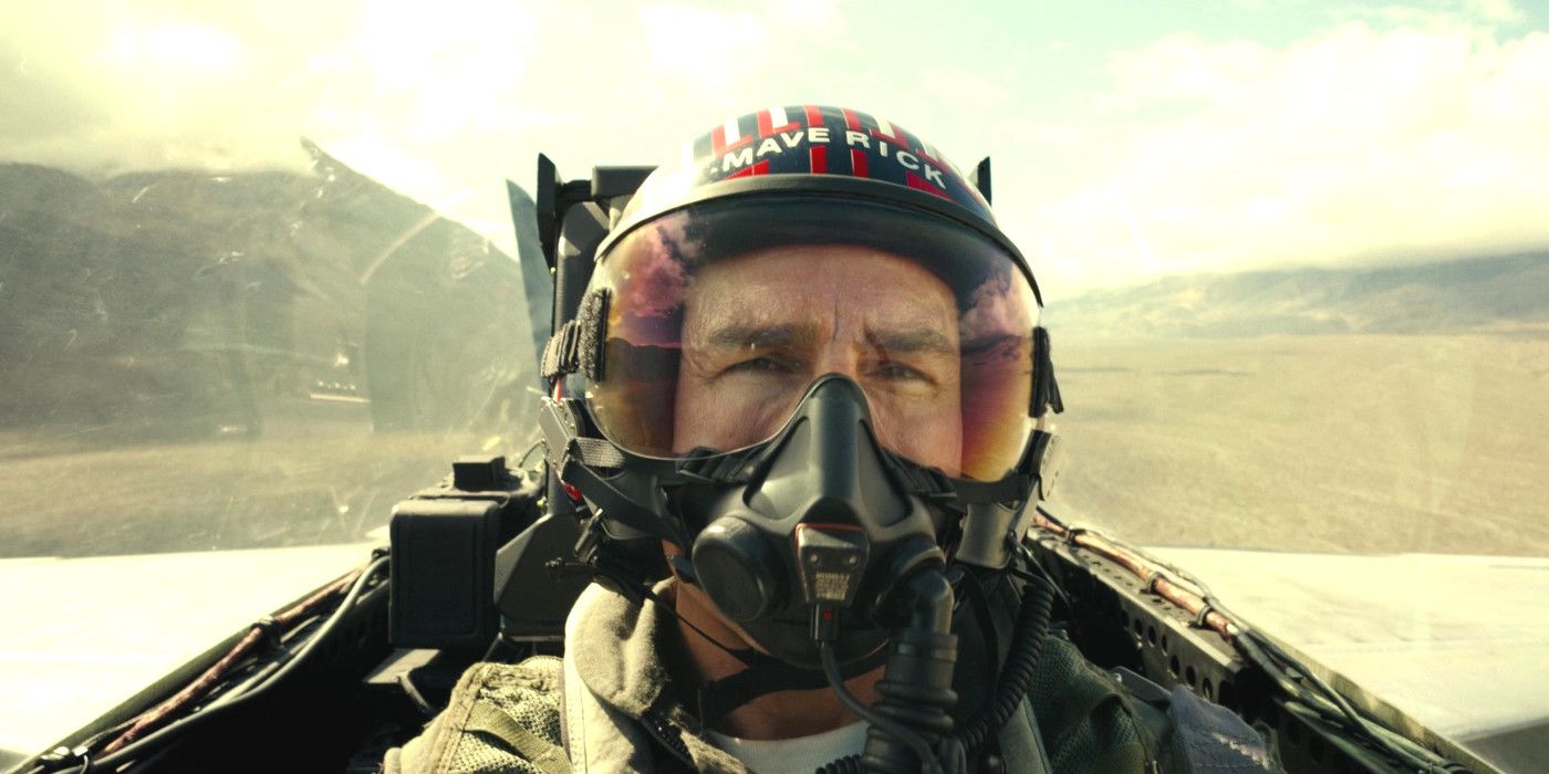 Tom Cruise in Top Gun Maverick in an action shot in a plane cockpit, wearing a helmet and oxygen mask