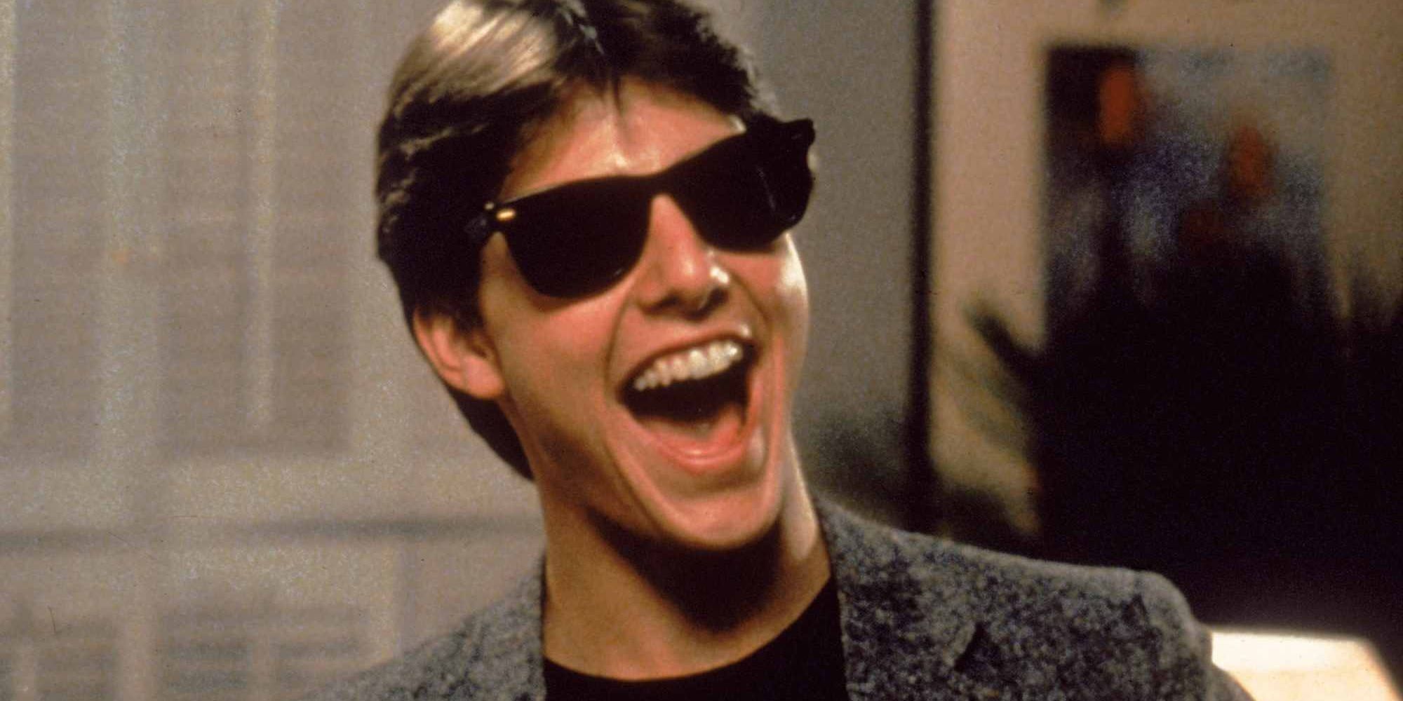 Tom Cruise wears sunglasses and smiles wide in Risky Business.