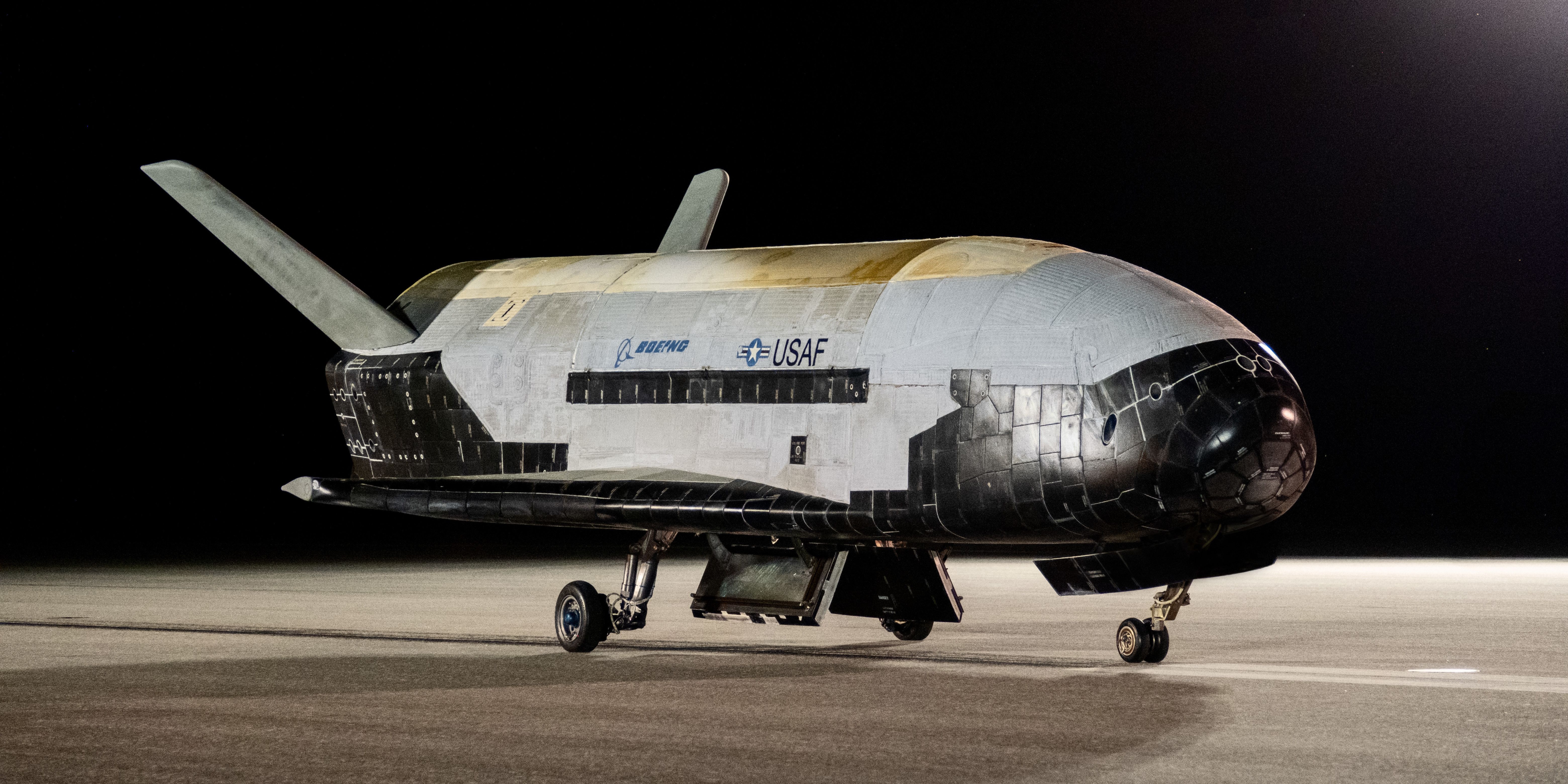 The X-37B spacecraft is pictured on the airstrip against a dark night sky